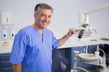 Portrait of a friendly dentist holding light